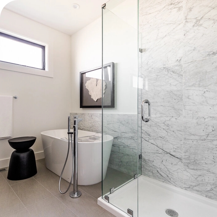 A white bathroom with a glass door shower and white soaking tub