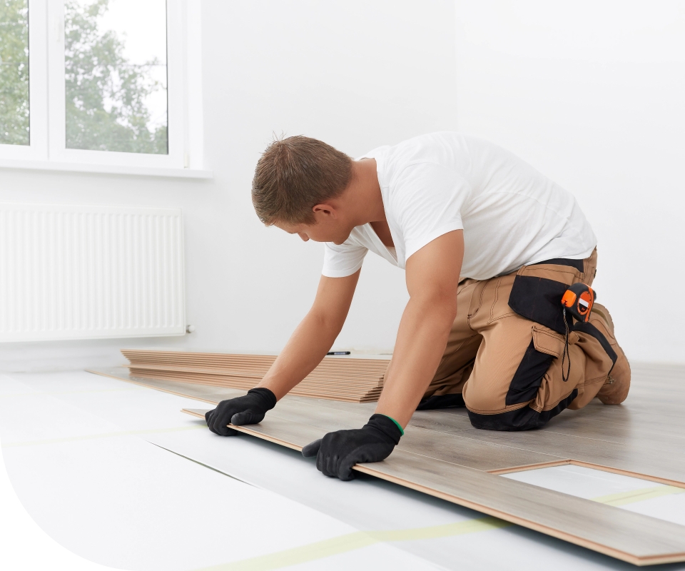 Man installing flooring in a white room 